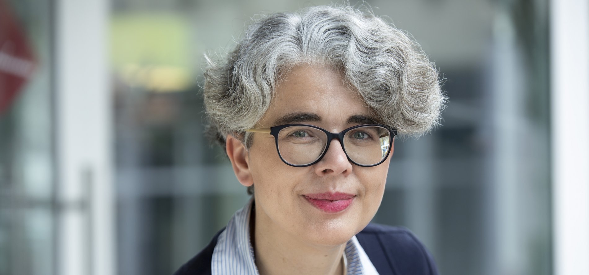 Eine Frau mit grauen Haaren und Brille.