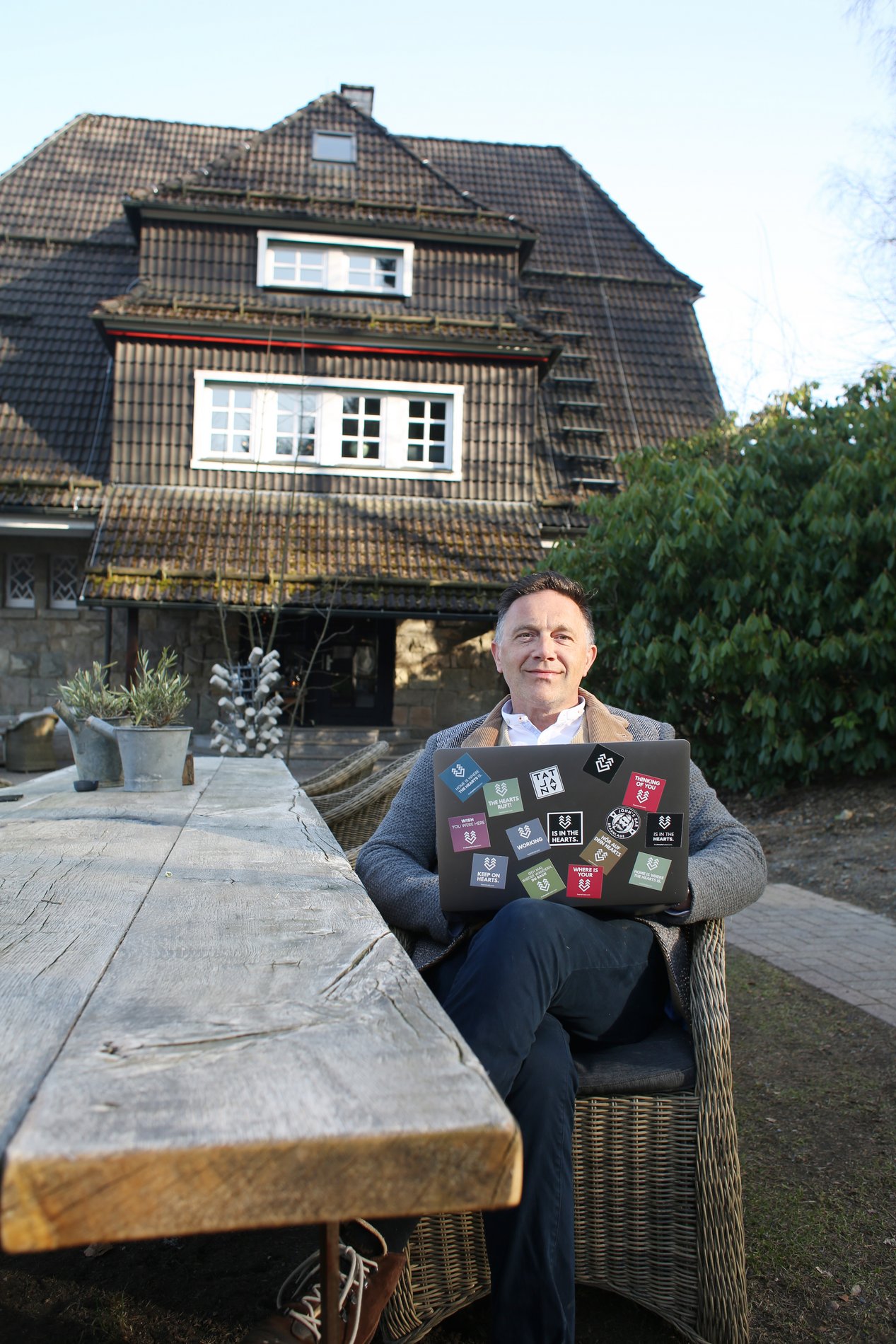 Ein Mann sitzt mit Laptop vor einem alten Hotel im Harz.