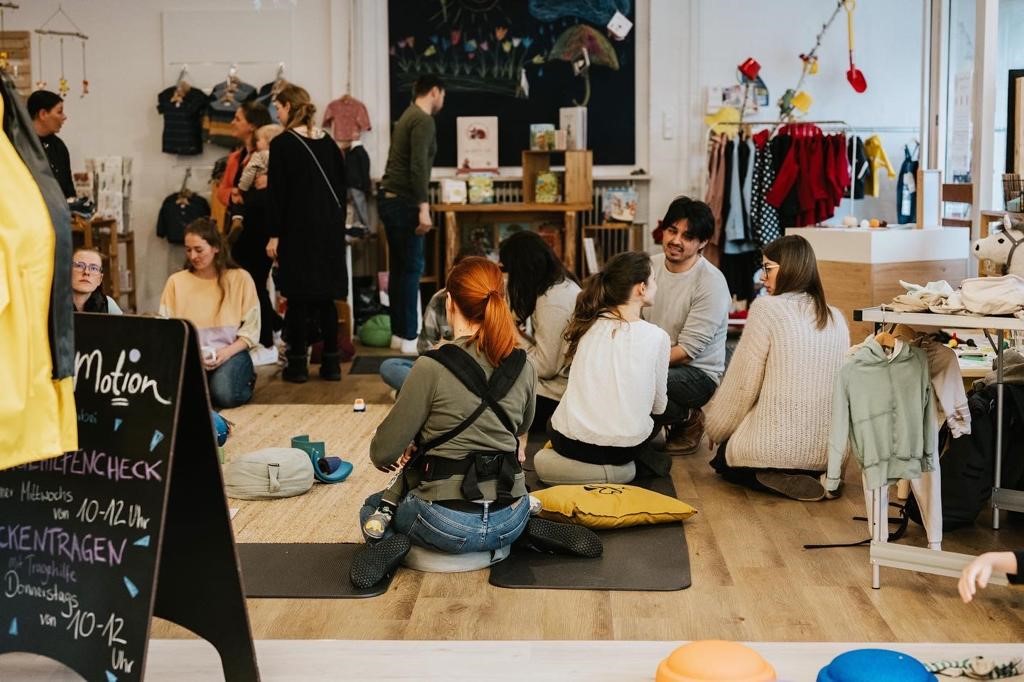 Eine Gruppe junger Eltern mit Kindern bei einem Treffen der Familienlounge.