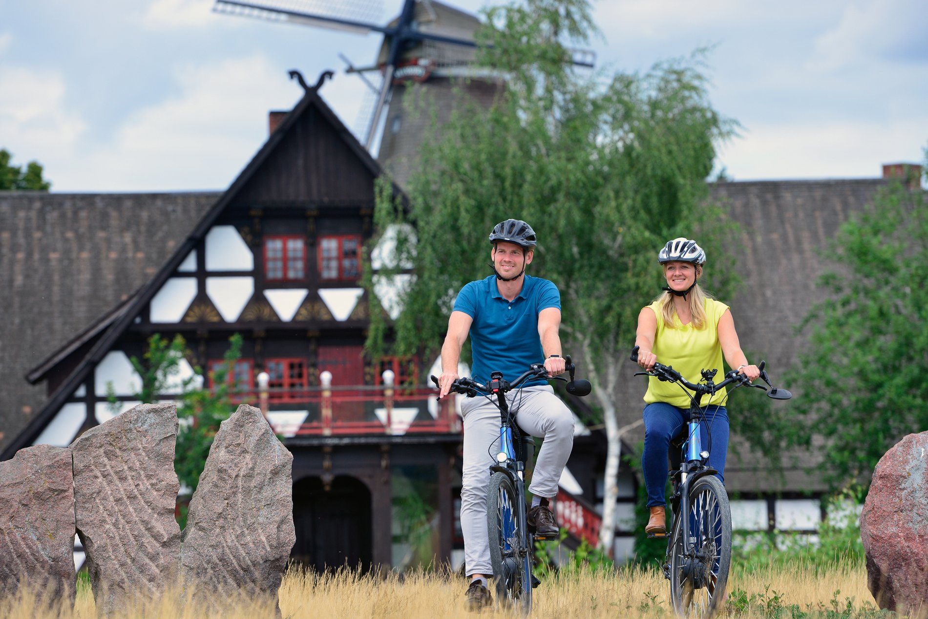 Ein Paar macht eine Rad Tour, im Hintergrund das Mühlenmuseum.