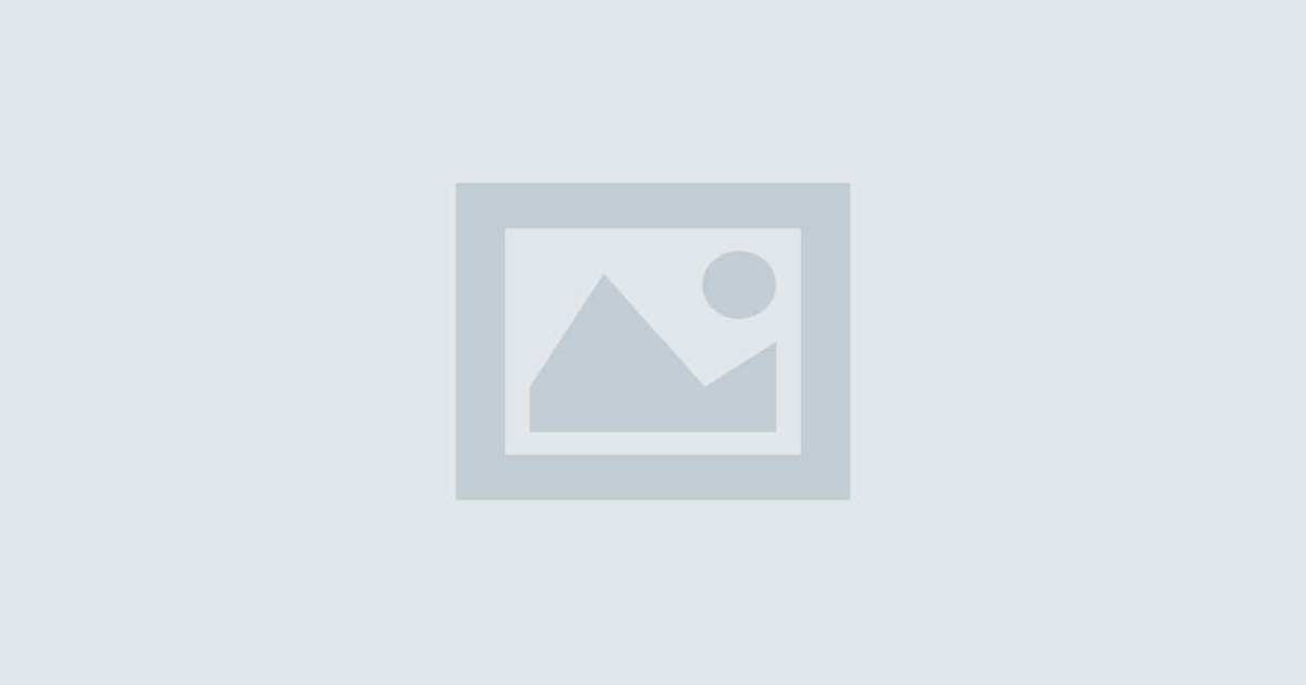 Eine Frau in Schürze vor einem Regal mit Senfgläsern.